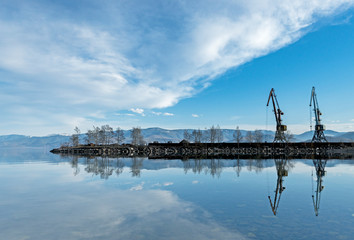 Two cranes near the water against the blue sky