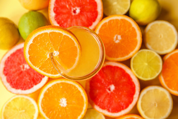 Colorful sliced citrus - oranges, grapefruits, lemons and limes close-up around a glass of orange juice and a slice of orange. Filled frame, top view