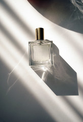 a round bottle of woman's fragrance resting on a box in light shining in from a window