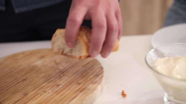 A man puts sliced baguette pieces on a white plate.