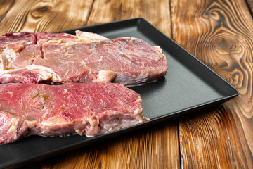 Two raw beef steaks on dark wooden table