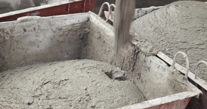 Liquid cement mortar poured into metal building pallet, technology for delivering materials to construction site, filling out form, mortar for laying bricks, construction site, close-up, gray slurry
