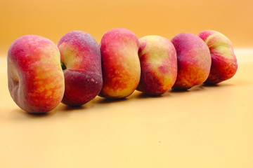panoramic closeup of ripe fresh fruit  flat peaches in a row isolated with nobody