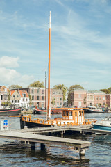 HAARLEM, NETHERLANDS, AUGUST 2019: Tourist Europe Travel Destinations. Attractive View of Harlem Sight With De Adriaan Windmill on Spaarne River On The Background At Noon