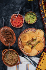Vegan Mexican gorditas along with refried beans, guacamole, tomato salsa and fried seitan pieces in traditional Mexican bowls