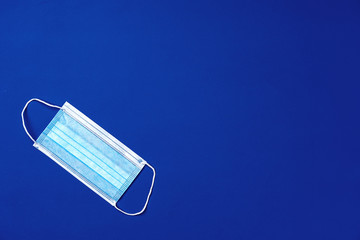 Medical face mask on blue background. Coronavirus prevention concept
