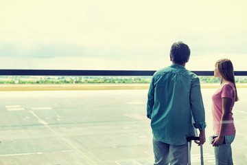 Rear view of mature man looking through the window with his daughter in airport
