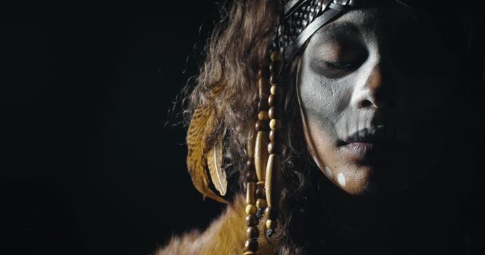 Beautiful young woman from a tribe is opening her eyes, face paint, 4k