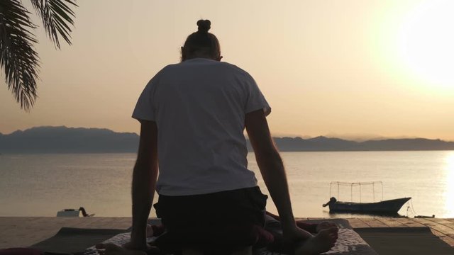 Rear view person doing massage for a woman at sunset seashore