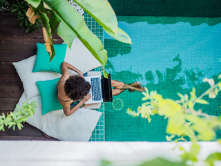 bird view of a remote online working digital nomad women with curly hair and laptop sitting at a...