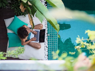 bird view of a remote online working digital nomad women with curly hair and laptop sitting crossed...