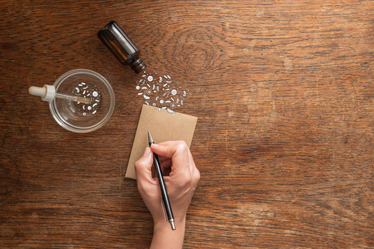 Skin care analysis concept research into the organisms that live on skin.  Microbiomes illustrated in dish and coming out of bottle.  Wooden natural background with space for copy text