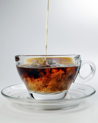 dark Coffee poring white milk dripping splash shadow liquid swirl in glass cup saucer on white background