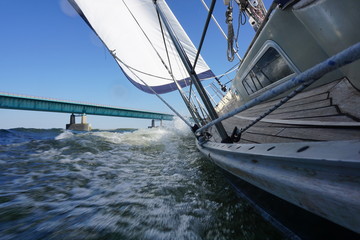 Sailing on sailboat with wind, waves and tube water with the Haringvliet bridge in the background.