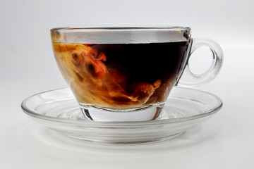 dark Coffee poring white milk dripping splash shadow liquid swirl in glass cup saucer on white background