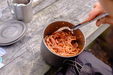 Cooked vermicelli with tomato paste during a picnic. Vermicelli is in a metal pot