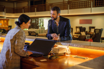 Businessman checking in at hotel. Young businessperson and receptionist at counter reception front...