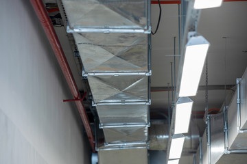 Obraz premium New installation of steel air conditioning duct pipes and lighted dumps, installation of ventilation ducts during the renovation of building.