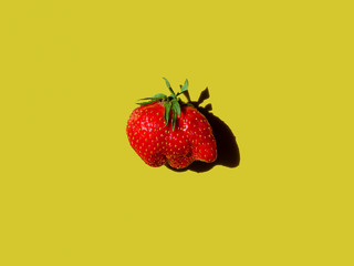 wrong shaped ugly strawberry on yellow bright background