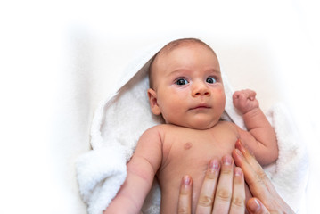 Adorable 2 months old little baby boy on towel after bath in his mother's hands