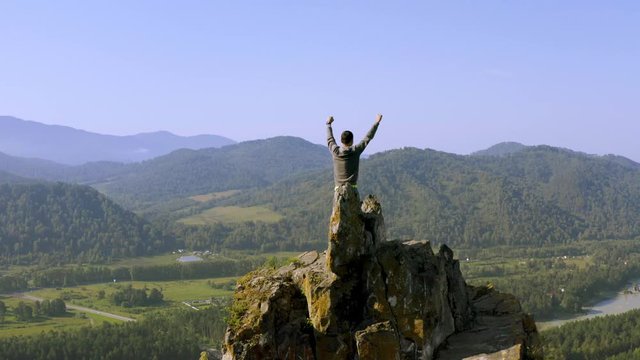 Man standing with raised hands on the top of Mountain Devil's finger peak. Altai
