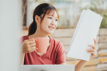 Asian woman reading document at her balcony in the morning