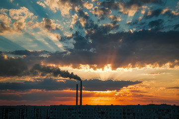 Colorful Magic Sunset. Roofs of city houses during sunrise. Dark smoke coming from the thermal power plant pipe.