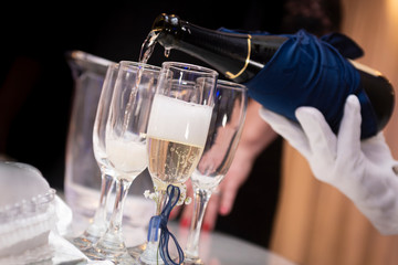 filling champagne glasses served by hand with white gloves to toast