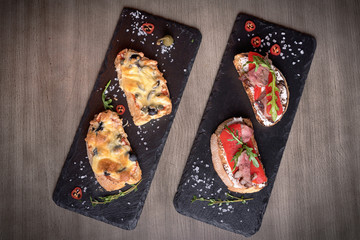 Four brutal sketches of meat and cheese on stone plates. restaurant giving. for the menu of cafe. wooden table