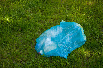 blue bag with garbage on the green grass