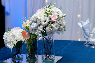 natural flowers in glass vases on a table with blue tablecloth on the main table of an event