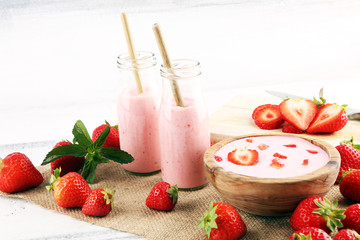 Glass of fresh strawberry shake, smoothie or milkshake and fresh strawberries on table. Healthy food and drink concept