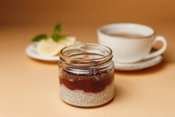 Chia pudding with berries, tea with lemon on an orange background