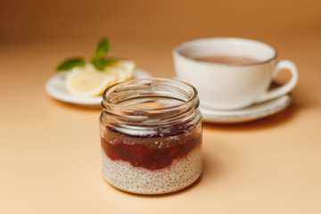 Chia pudding with berries, tea with lemon on an orange background