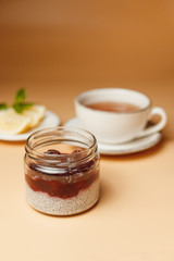Chia pudding with berries, tea with lemon on an orange background