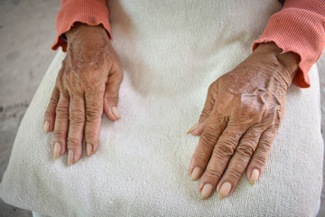 The hand of the sick old woman rests on the lap. Mental health care at home.