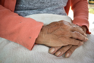 The hand of the sick old woman rests on the lap. Mental health care at home.
