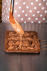 Process of making sweet chocolate sweets homemade. Chocolatier pours chocolate into molds.