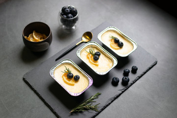 Homemade cheesecake with fresh blueberry and candied lemon on black stone background.