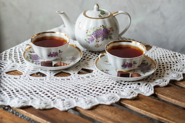 Traditional black tea. Tea ceremony. Two cups and saucer, teapot on a white lace tablecloth.