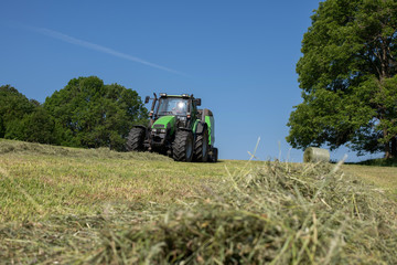 erster Grasschnitt, Traktor und Ballenpresse bei der Arbeit,
ernten und fertigen von Rundballen bei...