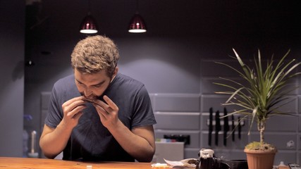 Attractive man makes a cigarette with tobacco and a piece of paper in quarantine self-isolation due...