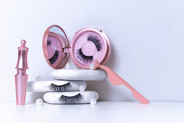 Magnetic fake artificial eyelashes in pink mirror kit, eye liner, tweezers on white background. Home eyelash extension, cosmetology tool concept, beauty treatment, improving physical appearance