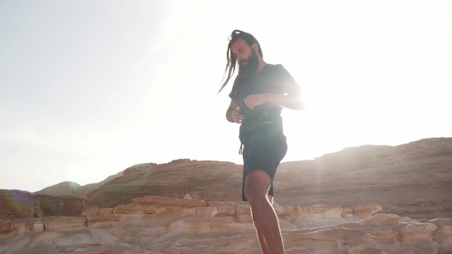 Bearded man practice ecstatic dance in desert in sunshine rapid slow motion
