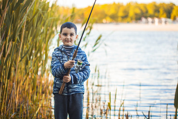 Cute boy catches fish on a summer lake. Activity in nature fishing. Happy childhood