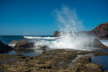 Fototapeta na wymiar the rocky seaside of Lanzarote island with crashing waves on a sunny day with a blue sky 