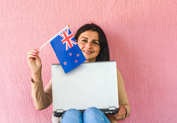 woman with laptop computer and flag of  New Zealand 