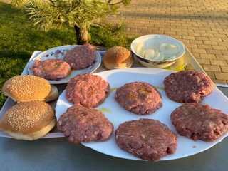 cooking a homemade burger outdoors. raw burger ingredients top view, outdoors homemade process of cooking on the yard during quarantine.