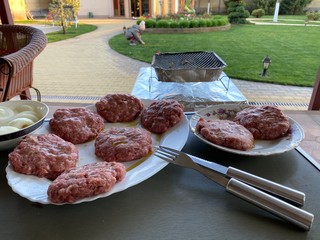 cooking a homemade burger outdoors. raw burger ingredients top view, outdoors homemade process of cooking on the yard during quarantine.