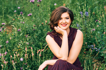 Outdoor summer portrait of beautiful woman posing between wildflowers